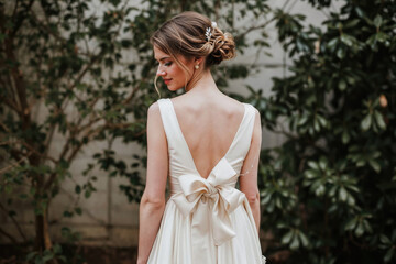 Bride in a white dress with a bow on the back standing outdoors. - Powered by Adobe