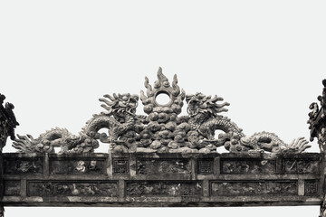 Intricate stone dragon and cloud carvings adorning an ancient tomb gate in Hue city, Vietnam
