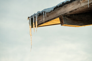 Eiszapfen an Eck vom Holzdach mit Himmel im Hintergrund