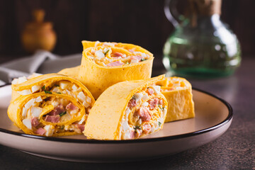 Tortilla rolls with salad of sausages, eggs, cheese and herbs on a plate