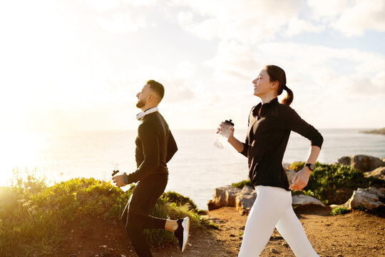 Man and woman jogging with water bottles at sunny day - Powered by Adobe