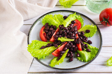 Vegetarian salad of black beans, tomatoes and lettuce on a plate