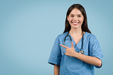 Confident nurse pointing to the side at free space, wearing scrubs