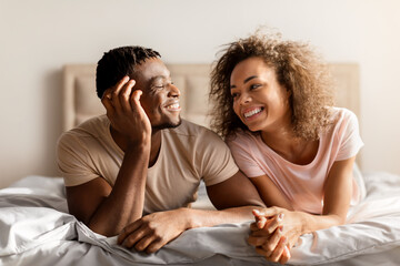 Obraz na płótnie Canvas Smiling African American Young Spouses Lying Together In Comfortable Bed