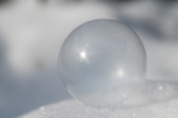 Close-up of a delicate soap bubble that is frozen. The background is light-coloured. The soap...