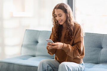 Obraz premium Carefree caucasian teenager girl with mobile phone relaxing at home