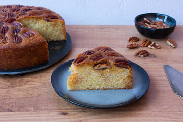 Portion of pecan pie on plate, on wooden table and white background