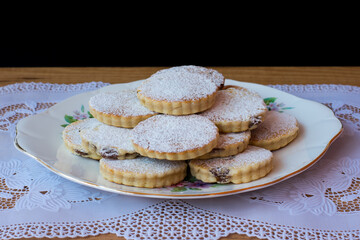 Pile of Welsh cakes on a white plate, black background