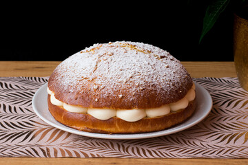 Sponge cake with icing sugar in top filled with cream on a white plate