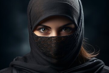 Naklejka premium a girl in a balaclava. portrait. knitted black headdress covering the face. the look of blue eyes.
