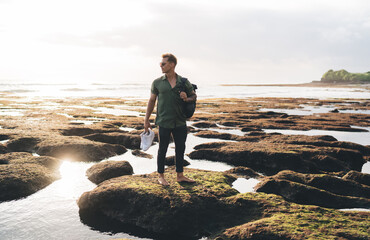 Attractive man standing on rocky seashore admiring sea