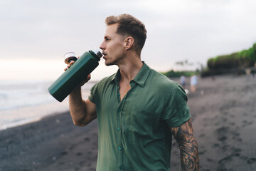 Man drinking water from bottle while on vacation at seashore