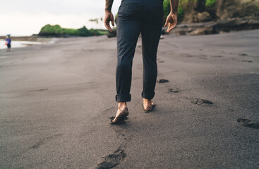 Crop unrecognizable person walking on sandy beach