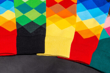 Arrangement of colorful socks with an argyle pattern on a black leather background