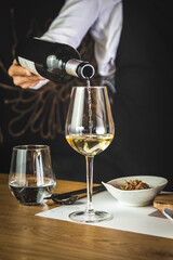 waiter pouring a white wine in to a wine glass in a restaurant