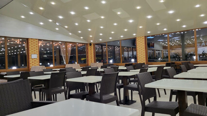 White empty tables with brown chairs in a cafe in the evening.