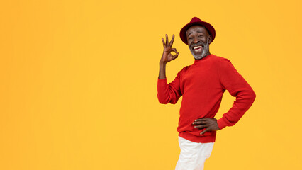 Smiling confident old black man in hat and red clothes, show ok sign with hand - obrazy, fototapety, plakaty