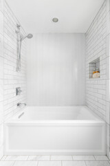 A bright, white shower with subway and herringbone tiles lining the shower walls and a niche with blank shampoo bottles.