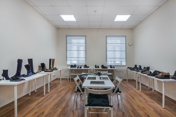 The interior of a modern showroom in bright colors with a table and chairs in the center .of the room.