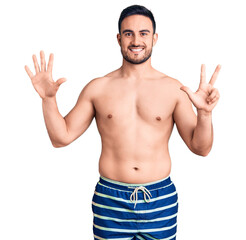 Fototapeta premium Young handsome man wearing swimwear showing and pointing up with fingers number eight while smiling confident and happy.