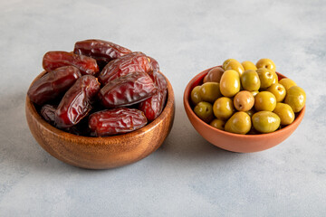 Date fruit with a bowl of green olive on light blue background .Top view