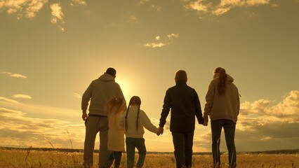 Big family plays in park at sunset, children, parents walk together under sun. Father, mother,...