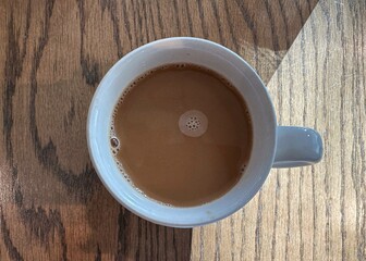 Cup of coffee and cream in a white ceramic mug on a wooden table