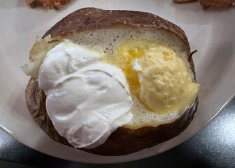 Baked russet potato with dollops of butter and sour cream