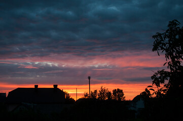 Abstract colorful background. Beautiful red sunset over a small town. Dramatic sunset sky with clouds.
