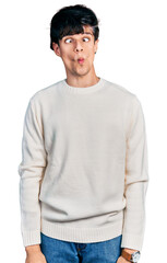 Fototapeta premium Handsome hipster young man wearing casual winter sweater making fish face with lips, crazy and comical gesture. funny expression.
