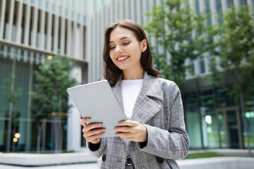 Fototapeta premium business lady happily browsing on digital tablet computer, standing outside