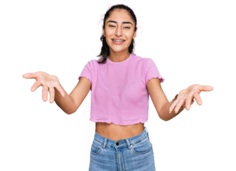 Hispanic teenager girl with dental braces wearing casual clothes smiling cheerful offering hands giving assistance and acceptance.