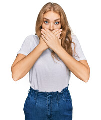 Young caucasian girl wearing casual white t shirt shocked covering mouth with hands for mistake. secret concept.