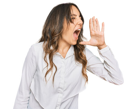 Young brunette woman wearing casual clothes shouting and screaming loud to side with hand on mouth. communication concept.