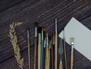 Bunch of art brushes on a wooden table, top view. Accessories for artists, working tools....