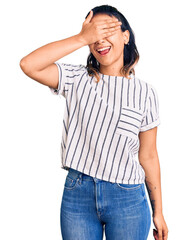 Young woman wearing casual clothes smiling and laughing with hand on face covering eyes for surprise. blind concept.