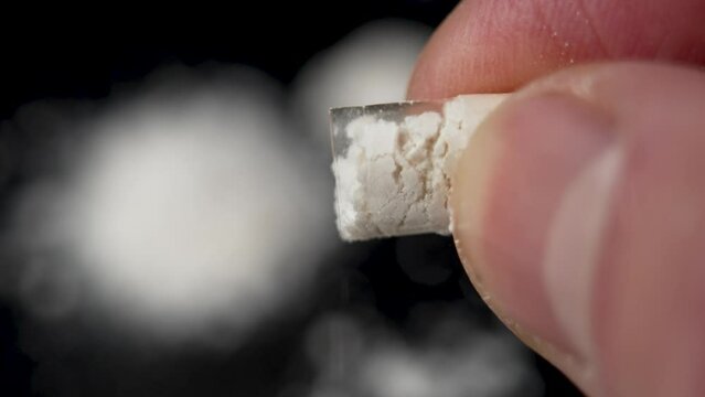 White chemical powder pours out from an open narcotic capsule in hand. Drug addiction concept