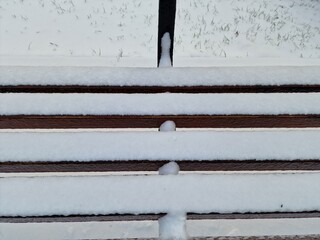 snow lies on a wooden bench in the park