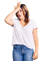 Fototapeta premium Young beautiful caucasian woman wearing casual white tshirt surprised with hand on head for mistake, remember error. forgot, bad memory concept.