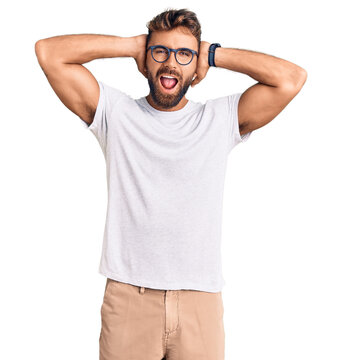 Young hispanic man wearing casual clothes and glasses crazy and scared with hands on head, afraid and surprised of shock with open mouth