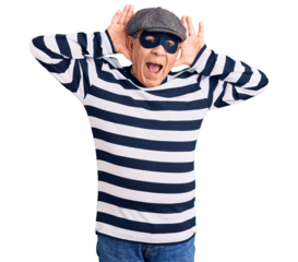 Senior handsome man wearing burglar mask and t-shirt smiling cheerful playing peek a boo with hands showing face. surprised and exited