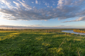 Epic view of water meadows, evening near the river, lush greenery illuminated by the rays of the...
