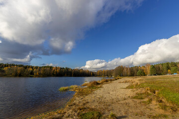 Bright autumn landscape with a river and a blue sky with clouds. abandoned beach by the lake