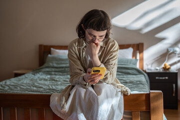 Nervous, stressed teen girl in glasses reading messages in smartphone feeling bad, humiliated. Depressed frustrated woman receive negative message in social media from haters. Cyberbullying, stalking.