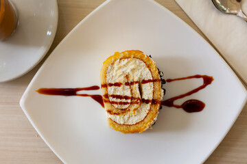 Fototapeta premium Delicious roll sponge cake with vanilla cream and chocolate sauce