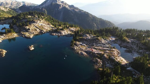 Couple paddleboarding on an alpine lake in the mountains with rocky shore