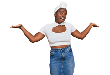 Young african woman with turban wearing hair turban over isolated background clueless and confused expression with arms and hands raised. doubt concept.