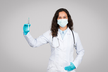 Doctor with mask holding syringe for injection