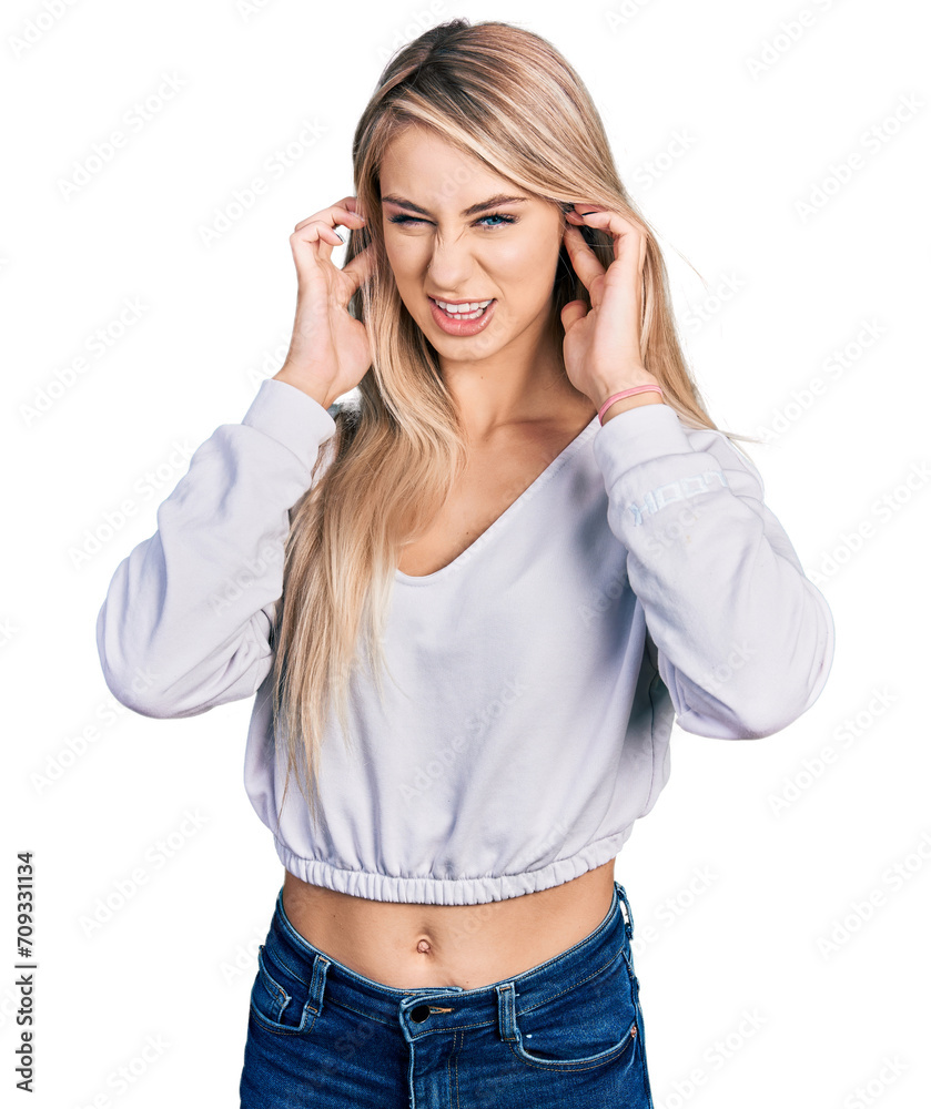 Poster Beautiful young blonde woman wearing casual white sweater covering ears with fingers with annoyed expression for the noise of loud music. deaf concept.