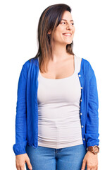 Young beautiful woman wearing casual clothes looking away to side with smile on face, natural expression. laughing confident.